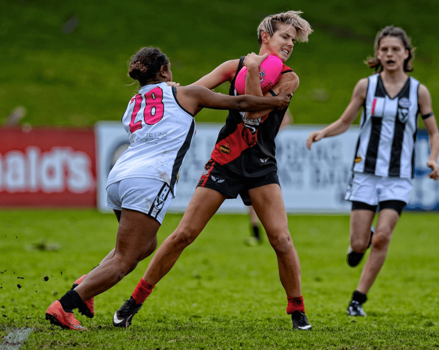 Blog photo - Two WAWFL football players from opposing teams tackling during a game